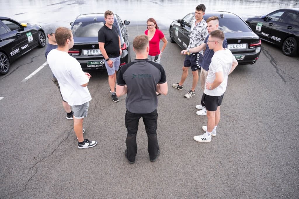 Einweisung der Teilnehmergruppe im Kreis zwischen den Trainingsfahrzeugen