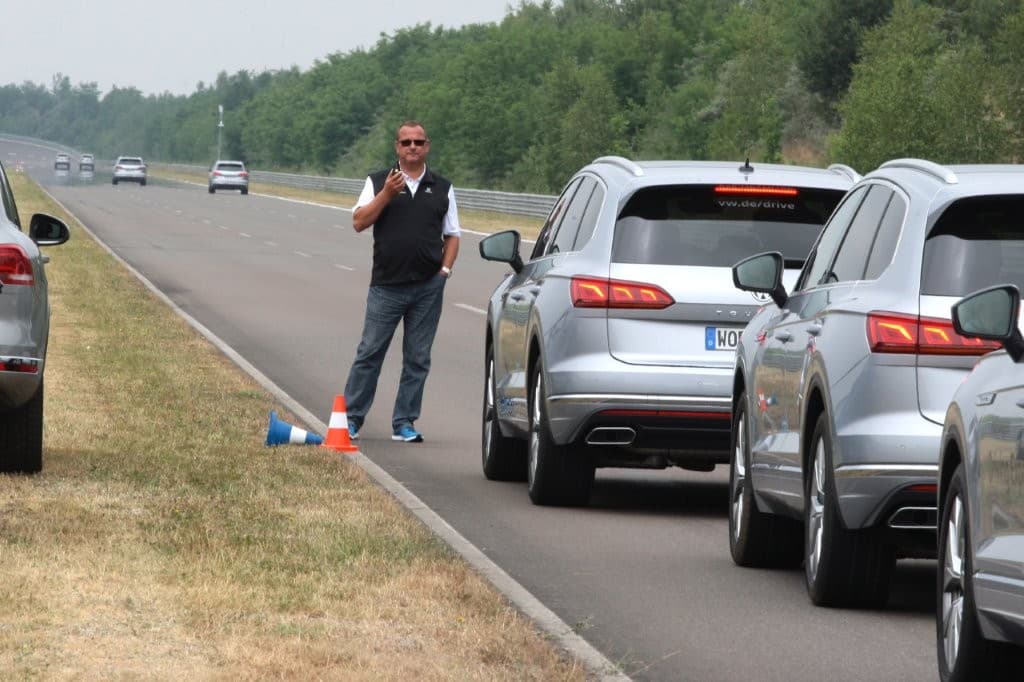 Fahrzeugkolonne am Streckenrand, der Trainer koordiniert die Gruppe per Funkgerät